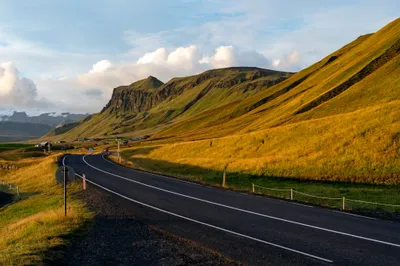 Winding road through golden hills and mountain ridges in Iceland